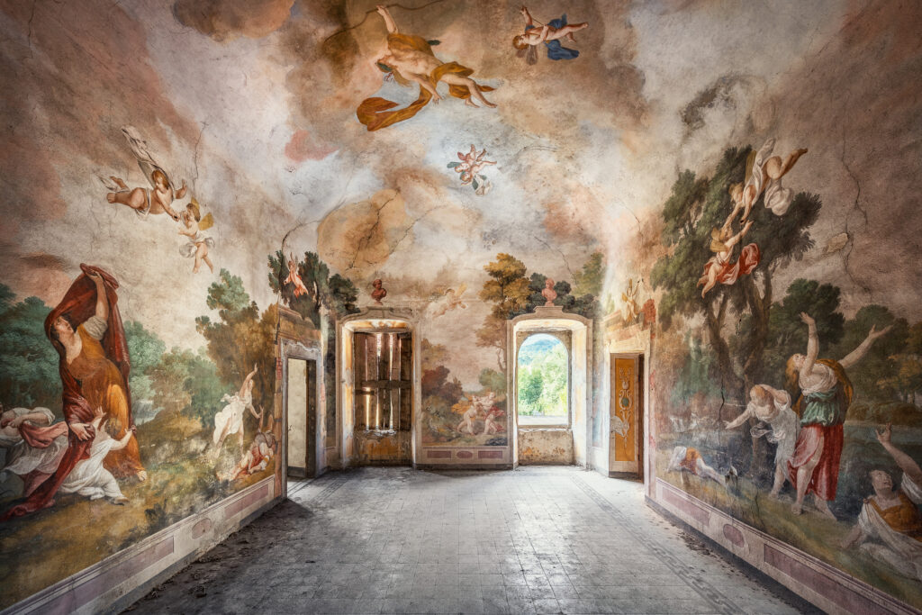 Eine teils verfallene Halle mit großflächigen Wand- und Deckenmalereien in barocker Manier